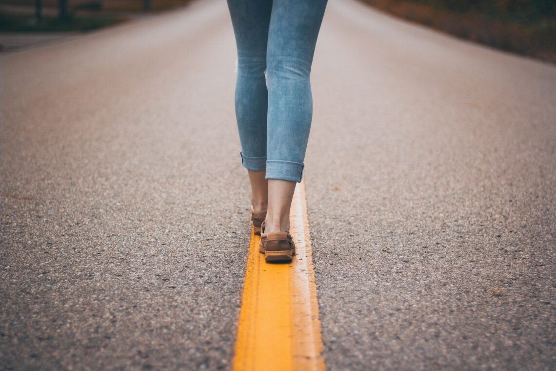 Woman walking on yellow line on empty street