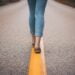 Woman walking on yellow line on empty street