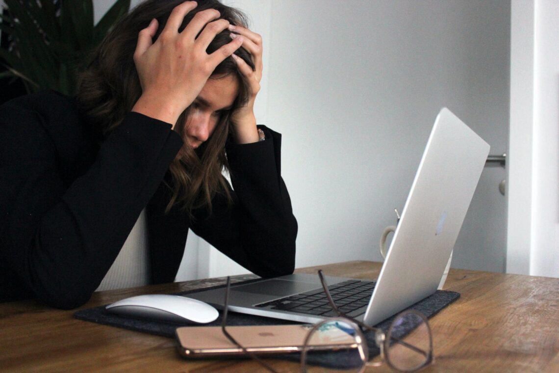 A business woman sitting behind laptop, who is stressed and frustrated