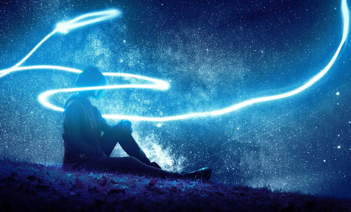 Person sitting on grass, surrounded by blue light at night